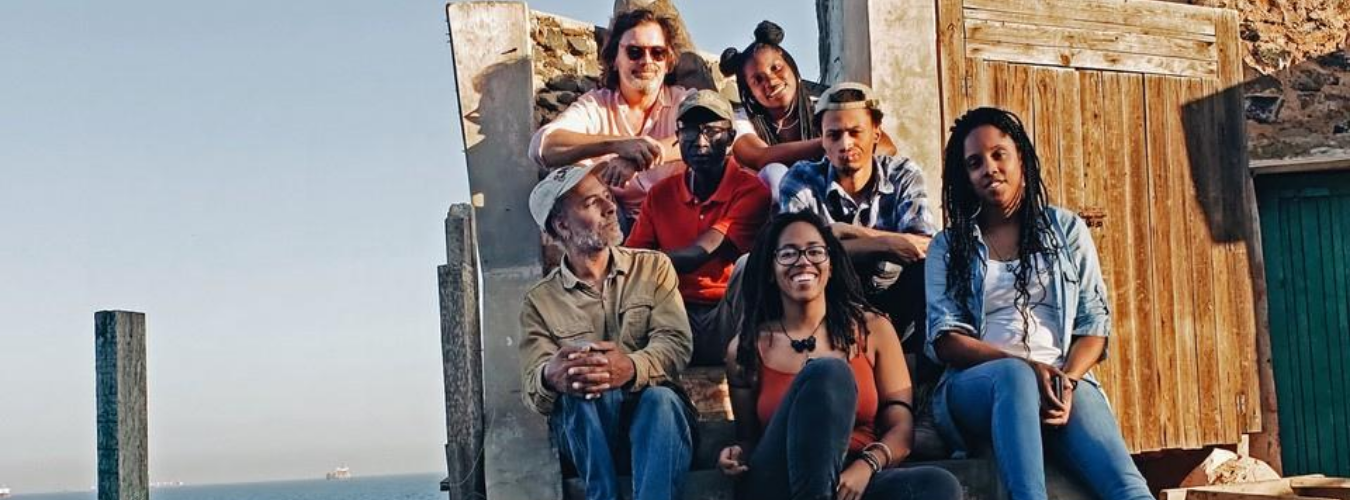 five art students with two professors sitting with an ocean behind them in Senegal